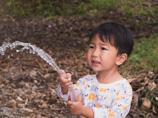 Asian Thai cute kid holding water hose