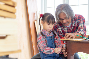 Asian carpenter and his daughter working on woodworking table in carpentry shop. Family, carpentry,...