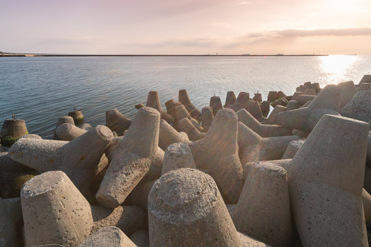 Tetrapod breakwaters in sea water. Beautiful sunset seascape with concrete tetrapodes for protect coastal structures from storm sea waves, effects of weather and longshore drift