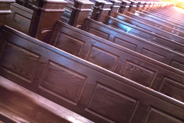 Cathedral benches. Rows of pews in christian church. Heavy solid uncomfortable wooden seats.