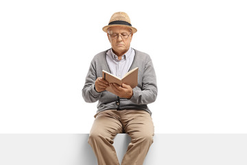 Elderly gentleman sitting on a panel reading a book