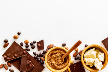 Chocolate with nuts and its ingredients on white background top view copyspace