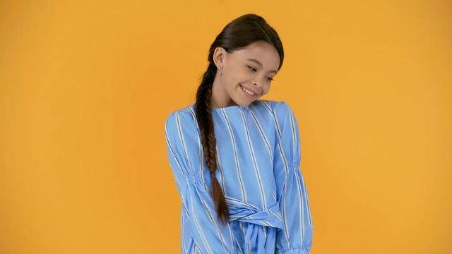 shy smiling preteen child in striped dress isolated on yellow