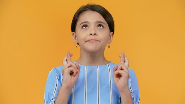 worried preteen child with crossed fingers isolated on yellow