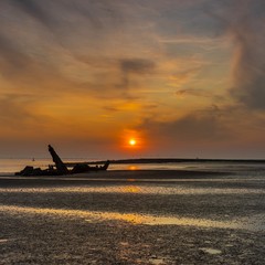 sunset behind an old shipwreck. Zeeland, The Netherlands