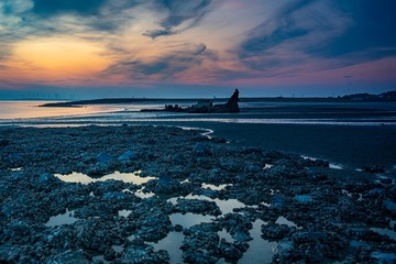 sunset behind an old shipwreck. Zeeland, The Netherlands 