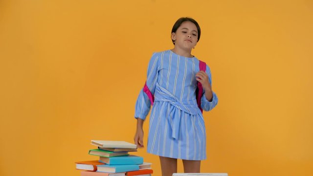 tired schoolgirl in blue dress taking out books from backpack