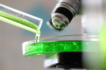 Microscope with green substance pouring out from test tube © megaflopp