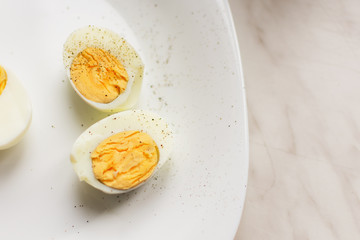Two halves of hard boiled eggs on white ceramic plate top view. Nutrition concept.