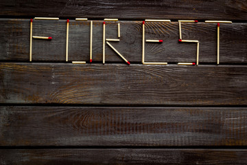 Fire concept with forest text on wooden background top view mock up