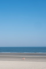 Fototapeta na wymiar few people on large sandy beach of german island norderney off the coast of ostfriesland under blue sky in summer
