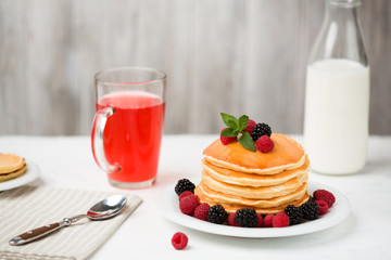 Homemade pancakes with berries and honey on a light background