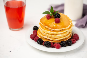 Homemade pancakes with berries and honey on a light background