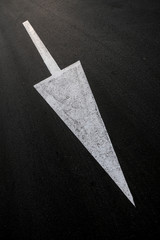 Fototapeta premium Long white arrow on black background, diagonal composition, angled perspective, vertical frame.