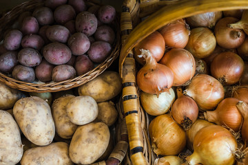 varieties of raw potatoes and onions in baskets in a health food store