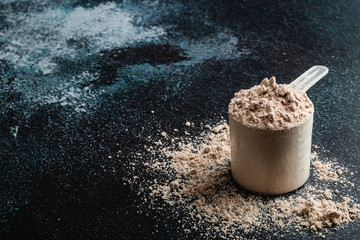 Top view whey protein scoop on dark background, copy space