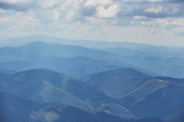 Landscape of Carpathian Mountains with blue silhouettes of hills and mountains with blue sky.