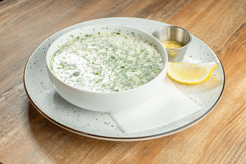 Close up on bowl with okroshka - A cold soup made of kvass or serum with different herbs and finely chopped meat or fish. Russian cuisine. Food photo background fore recipe or menu