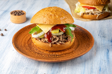Fresh and tasty burger with roast beef, onion, asparagus and cheese on blue wooden background. American traditional fastfood. Food photo background. Cheeseburger, Chickenburger