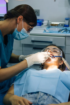 process of placing white dental braces to a Caucasian girl in a dental clinic with a dentist girl
