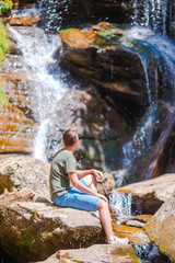 Man enjoying view of waterfall in gungle