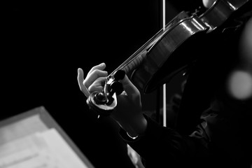 The hand of a girl playing the violin in black and white tones