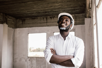 African construction engineer smiling while wearing helmet.