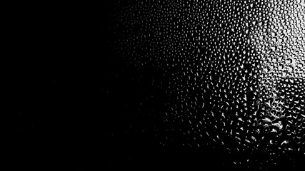 Raindrops on the surface of the window panes with a black background. Natural rain pattern on the glass. Light penetrates through water droplets. Horizontal background for website design