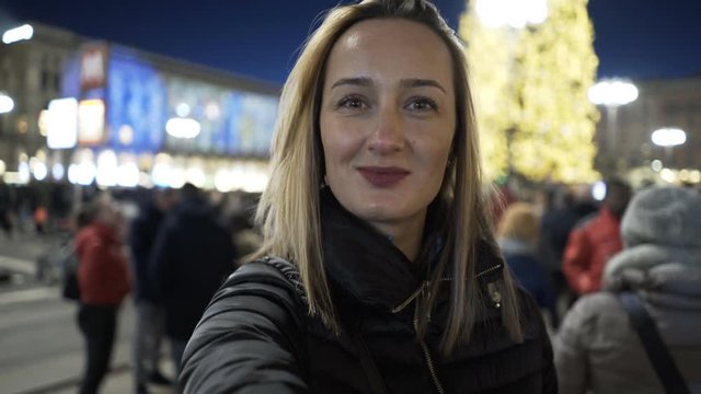 Young, happy woman recording selfie video walking in city