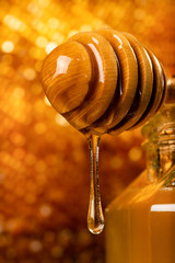 the honey flows gently from the wooden ladle in the foreground