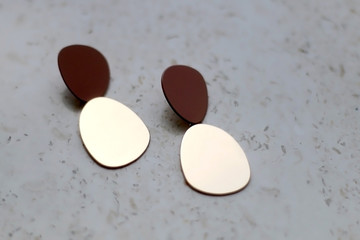 Trendy gold earrings on marble background. Selective focus.