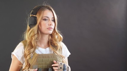 Brave amazing army girl wearing military plate carrier upon white t-shirt. Female ranger posing isolated on black studio background