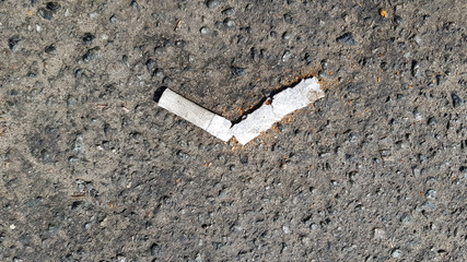 Close up of a broken cigarette butt on asphalt with copy space. International No Tobacco Day. World Day against cigarettes, nicotine and tobacco