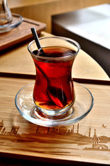 Turkish tea, a glass with tea on a wooden tray in a cafe.