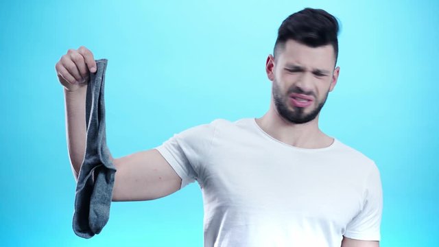 man holding smelly socks on blue 