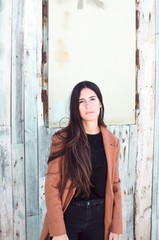 Fototapeta premium long-haired young woman wears trench coat and looks at camera