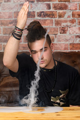 Vaper Smoke outdoor electronic cigarette near the brick wall. Young man smoking big cloud of steam