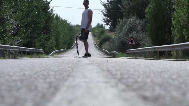 Man walking along the road with a helmet in his hand and a prothesis in his leg