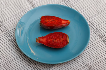 View from above of two halves of a red indian fig (also called prickly pear) on a blue plate.