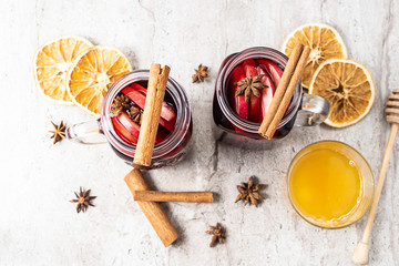 Hot aromatic mulled wine with honey, spices and fruits on the table top view. Traditional aromatic...