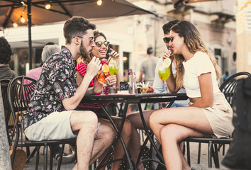 A group of people having fun in an outdoors city pub drinking cocktails and aperitifs. Millennial people drinking alcoholic drinks lifestyle concept.