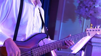 A man plays the guitar to the saxophone at a closed nightclub party. Guitar close up
