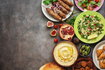 Arabic and Middle Eastern dinner table. Hummus, tabbouleh salad, Fattoush salad, pita, meat kebab,...