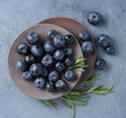 fresh sweet blueberries in gray plate on pure blue wood table top view copy space rustic