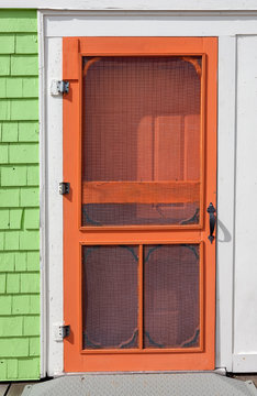 Old-fashioned wooden screen door painted bright orange.