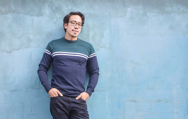 Obraz na płótnie Canvas Attractive asian guy, leaning on a light blue wall