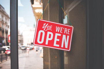yes we're open sign on the glass of the doors in store.  welcome sign at the store - obrazy, fototapety, plakaty