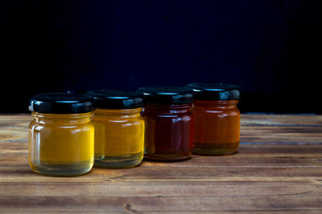 Little jars with honey different colours on wooden table