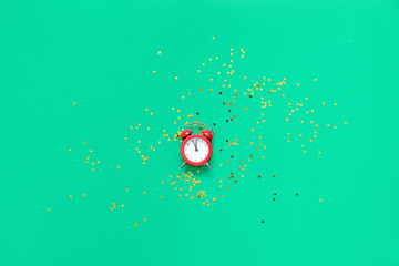 Red alarm clock on green background with golden glitter stars. 2020 new year or chritmas eve card