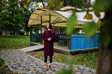 A tall leggy young beautiful and elegant model woman at claret coat.